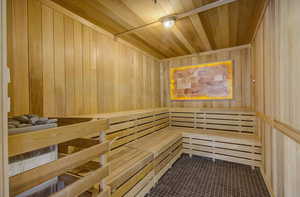 Relaxing sauna with wood walls, wooden ceiling, and tile patterned flooring