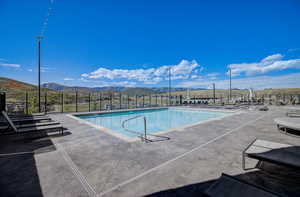 Community pool with fence, a mountain view, and a patio area