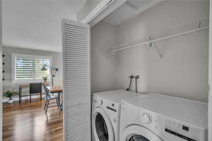 Laundry room with washer and dryer, wood finished floors, and a desk
