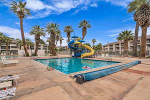 Community pool with a water slide and a patio
