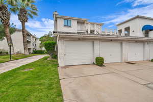Townhome / multi-family property with stucco siding, a balcony, a front lawn, and a chimney