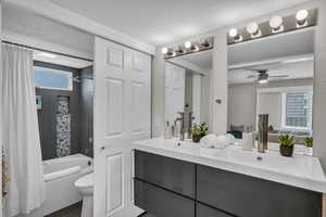 Full bath featuring double vanity, shower / bath combination with curtain, a textured ceiling, toilet, and a ceiling fan
