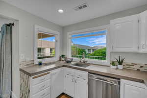 Kitchen featuring dishwasher, a sink, white cabinets, and recessed lighting