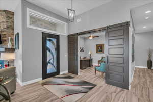 Foyer entrance with a barn door, baseboards, light wood-type flooring, and recessed lighting