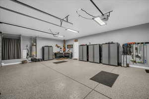 Garage with water heater, a garage door opener, and baseboards