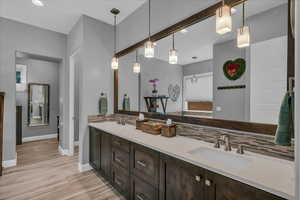 Full bath with baseboards, tasteful backsplash, double vanity, wood finished floors, and recessed lighting