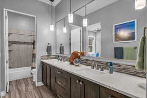 Bathroom with tasteful backsplash, double vanity, toilet, and shower / bathtub combination with curtain