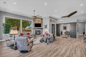 Living area featuring recessed lighting, baseboards, a fireplace, a ceiling fan, and wood finished floors