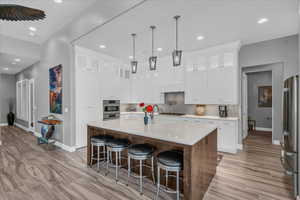 Kitchen featuring stainless steel appliances, baseboards, recessed lighting, backsplash, and white cabinets