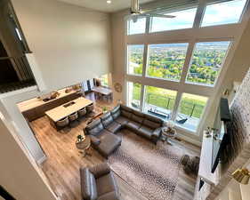 Living area with a high ceiling, wood finished floors, a ceiling fan, healthy amount of natural light, and recessed lighting