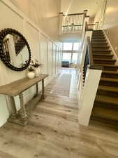 Hall with stairs, a high ceiling, and light wood-style floors