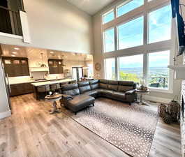 Living room with healthy amount of natural light, a high ceiling, light wood-style flooring, and baseboards
