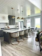 Kitchen with a sink, a large island, a breakfast bar area, decorative backsplash, and light wood finished floors