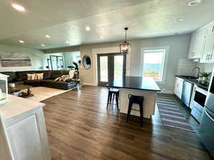 Living room with a textured ceiling, baseboards, dark wood finished floors, recessed lighting, and french doors