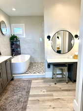 Bathroom with a freestanding tub, wood finished floors, and vanity