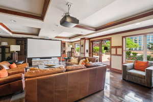 Cinema featuring crown molding, coffered ceiling, dark wood-style flooring, and french doors
