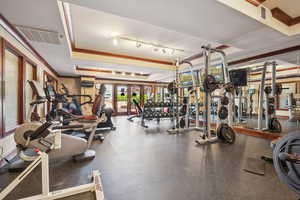 Gym featuring a tray ceiling and french doors