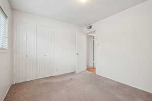 Unfurnished bedroom with carpet floors, a closet, multiple windows, and a textured ceiling