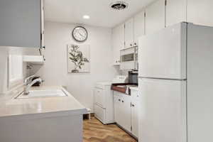 Laundry area with washer and dryer, light wood-style floors, and recessed lighting