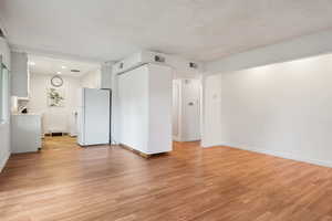 Unfurnished living room with light wood-type flooring, baseboards, and recessed lighting