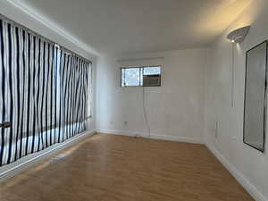 Unfurnished room with light wood-style floors, baseboards, and cooling unit