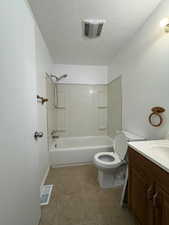 Bathroom featuring shower / washtub combination, toilet, vanity, and a textured ceiling