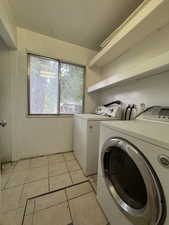 Laundry area featuring independent washer and dryer and light tile patterned floors