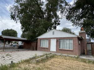 View of front of home featuring fence, a chimney, and brick siding