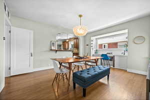 Dining space featuring wood finished floors, arched walkways, baseboards, and a chandelier