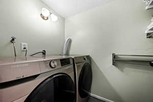 Clothes washing area featuring washing machine and clothes dryer and baseboards