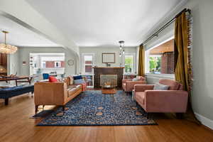 Living area with wood finished floors, a tile fireplace, and a chandelier