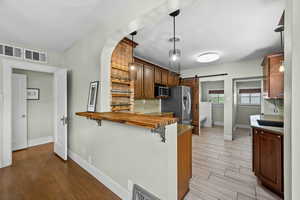 Kitchen with appliances with stainless steel finishes, light wood finished floors, a barn door, a breakfast bar, and backsplash