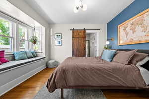 Bedroom featuring a barn door and wood finished floors