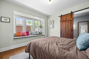 Bedroom with wood finished floors, baseboards, and a barn door