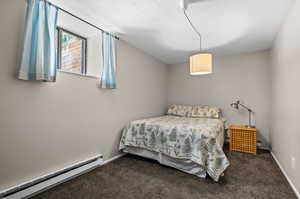 Bedroom with baseboard heating, dark carpet, a textured ceiling, and baseboards