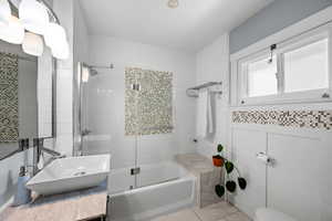Full bathroom with marble look tiles, combined bath / shower with glass door, and vanity