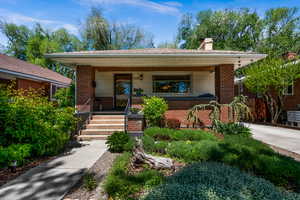 Bungalow-style house featuring a porch, a chimney, and brick siding