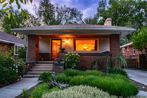 View of front of house with a porch, brick siding, and a chimney