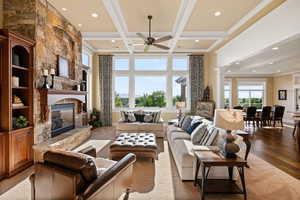 Living area featuring a stone fireplace, recessed lighting, ceiling fan, wood finished floors, and beam ceiling