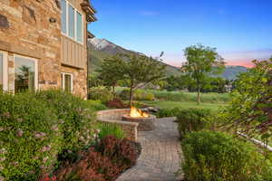 View of green lawn featuring an outdoor fire pit, a mountain view, and a patio area