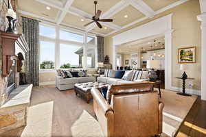 Living area with decorative columns, a ceiling fan, a towering ceiling, a fireplace, and baseboards