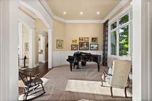 Home office with decorative columns, arched walkways, ornamental molding, wainscoting, and wood finished floors
