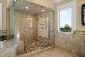 Bathroom with a stall shower, crown molding, and tile walls