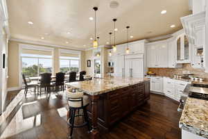 Kitchen featuring crown molding, dark wood-style floors, recessed lighting, tasteful backsplash, and white cabinets