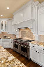 Kitchen with Wolf 60” dual-fuel range, white cabinets, and recessed lighting