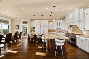 Kitchen featuring built in appliances, white cabinets, dark wood-type flooring, light stone counters, and recessed lighting