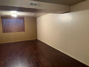 Spare room featuring dark wood-style floors and baseboards