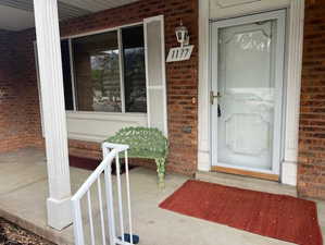 Doorway to property featuring brick siding and a porch