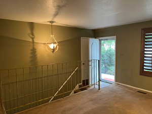 Foyer entrance featuring carpet floors, a textured ceiling, vaulted ceiling, and baseboards