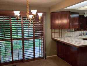Unfurnished dining area with carpet floors, a chandelier, and baseboards